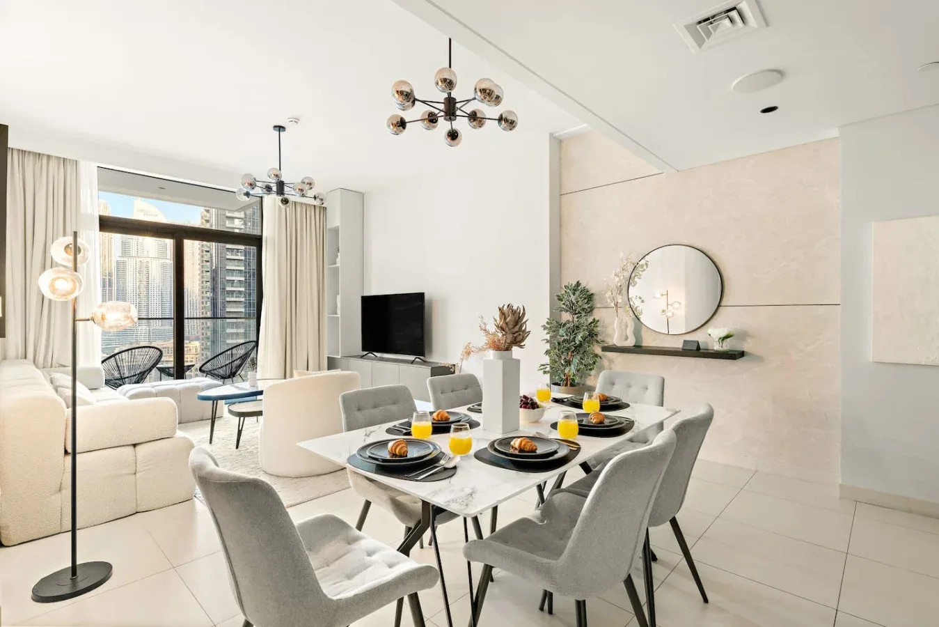 Una luminosa sala de estar y comedor diáfana, con la mesa puesta y grandes ventanales.