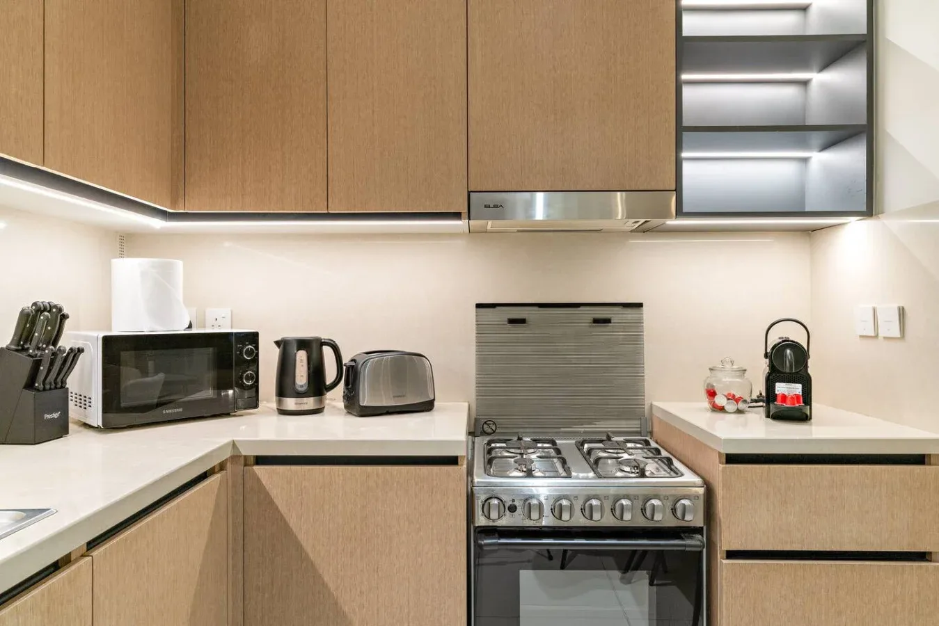 Una cocina moderna con gabinetes de madera, una estufa y electrodomésticos sobre la encimera.