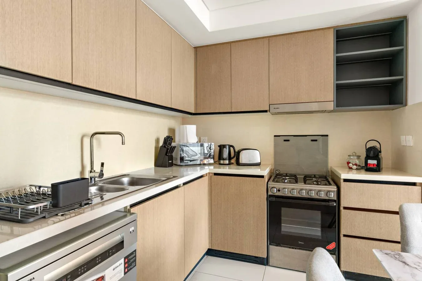 Una cocina con gabinetes de madera clara, un fregadero y una estufa independiente.