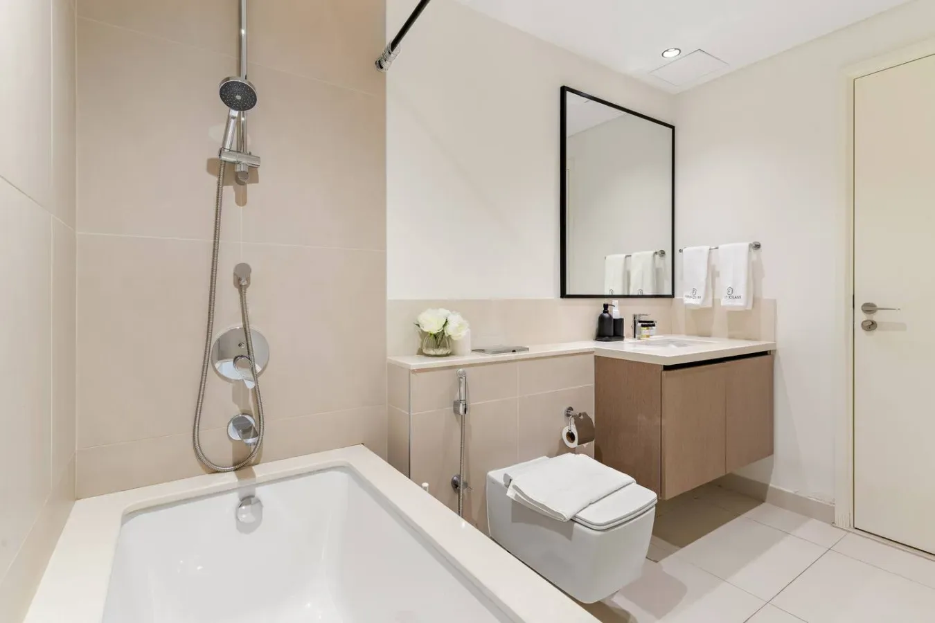 Un baño luminoso con bañera, ducha, inodoro y lavabo con mueble.
