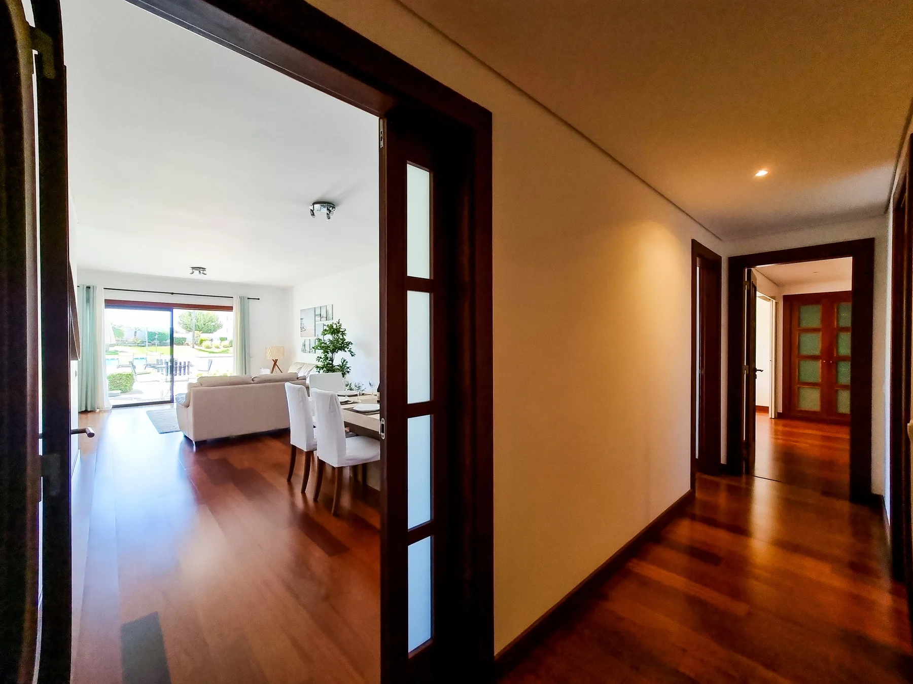 Un pasillo da a una sala luminosa con asientos y una mesa de comedor.