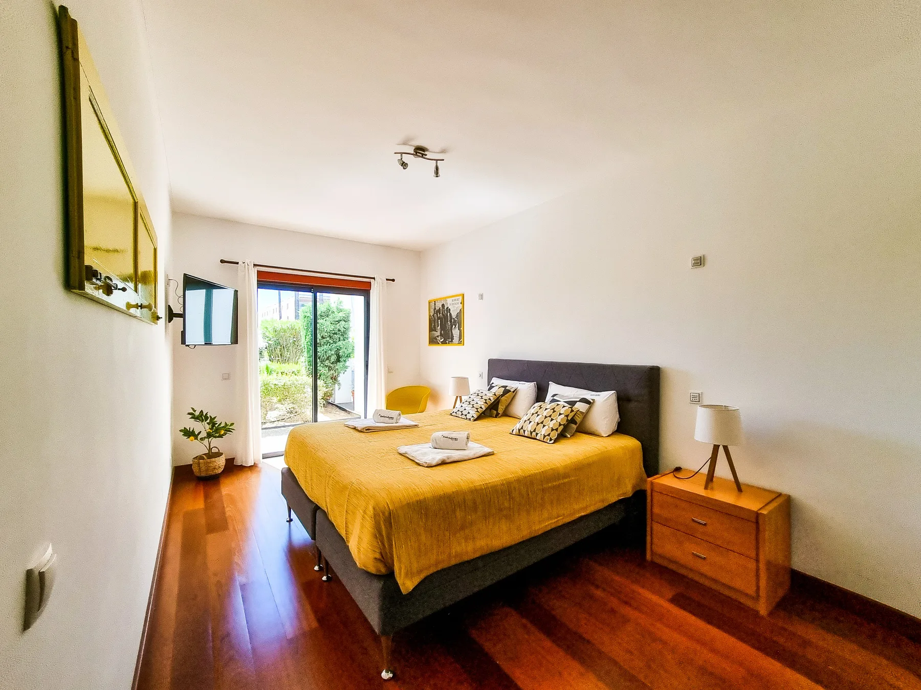 Un dormitorio con una cama doble y una puerta de cristal que da a una zona verde.