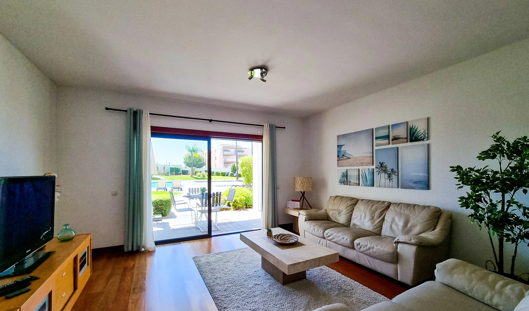 Sala de estar con asientos, una mesa de centro y puertas corredizas de vidrio hacia un patio.