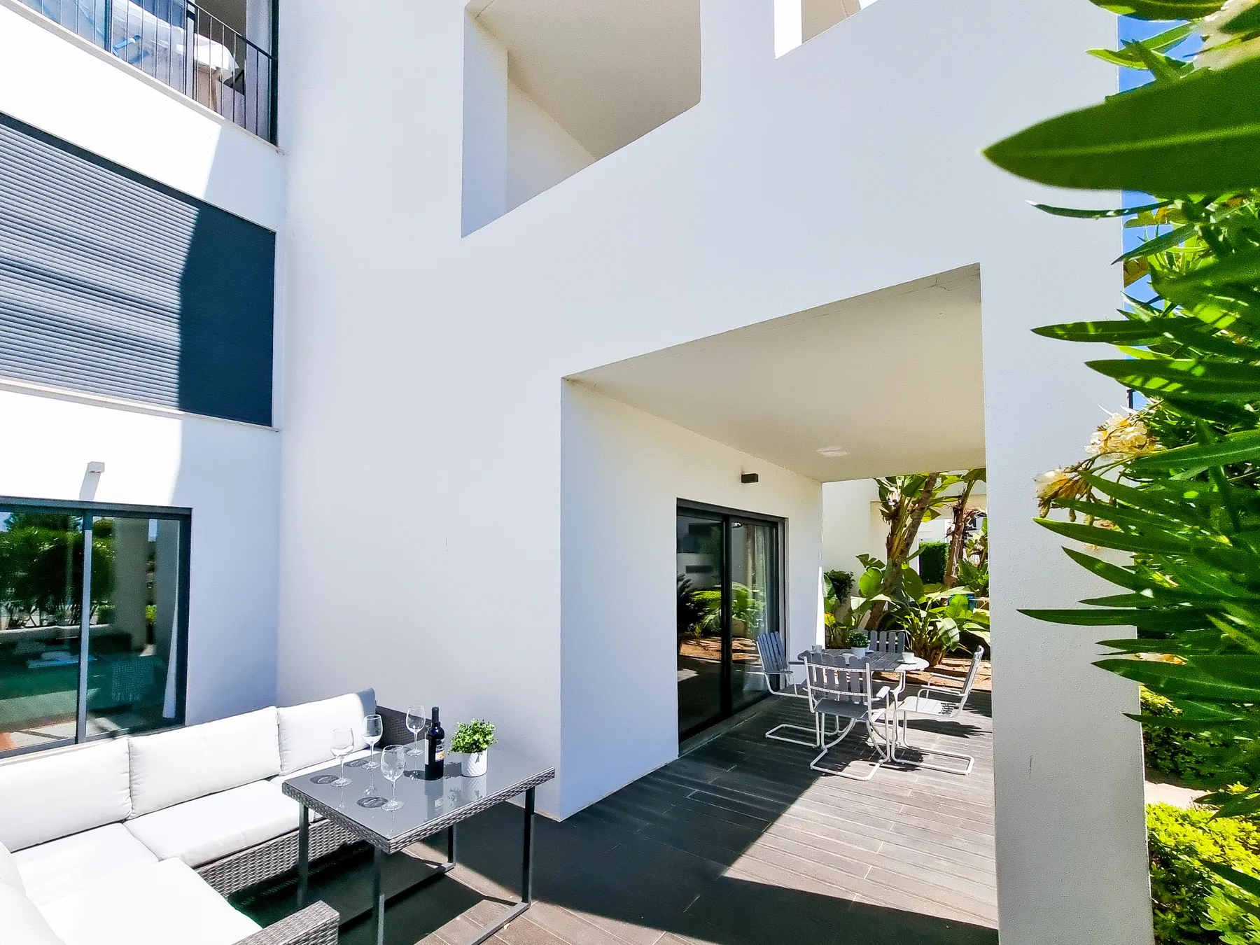 Un patio exterior moderno con asientos, una mesa y puertas corredizas de vidrio.