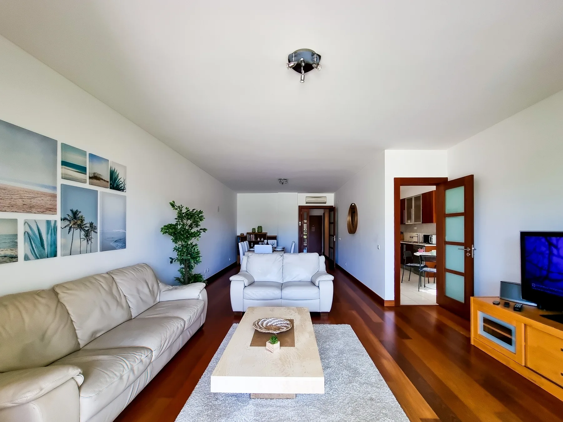 Una sala de estar luminosa con asientos, una mesa de centro y un televisor.