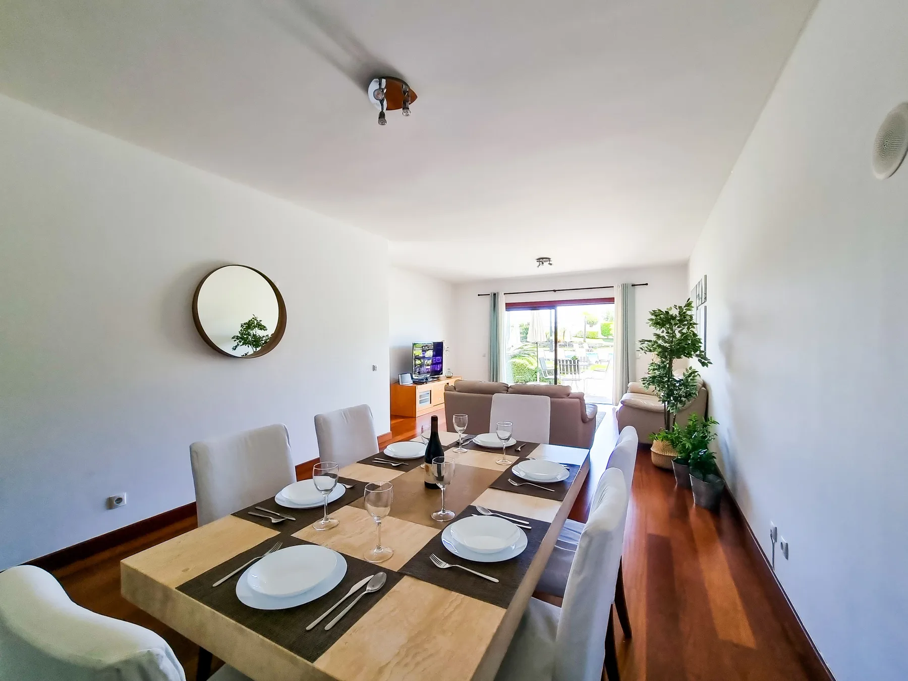 Una zona de comedor con la mesa puesta da a una sala de estar luminosa.