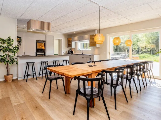 Una luminosa cocina abierta con comedor y una larga mesa de madera.