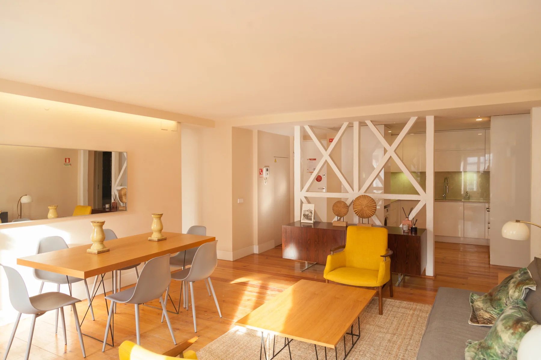 A bright living and dining area with a yellow armchair and wooden tables.