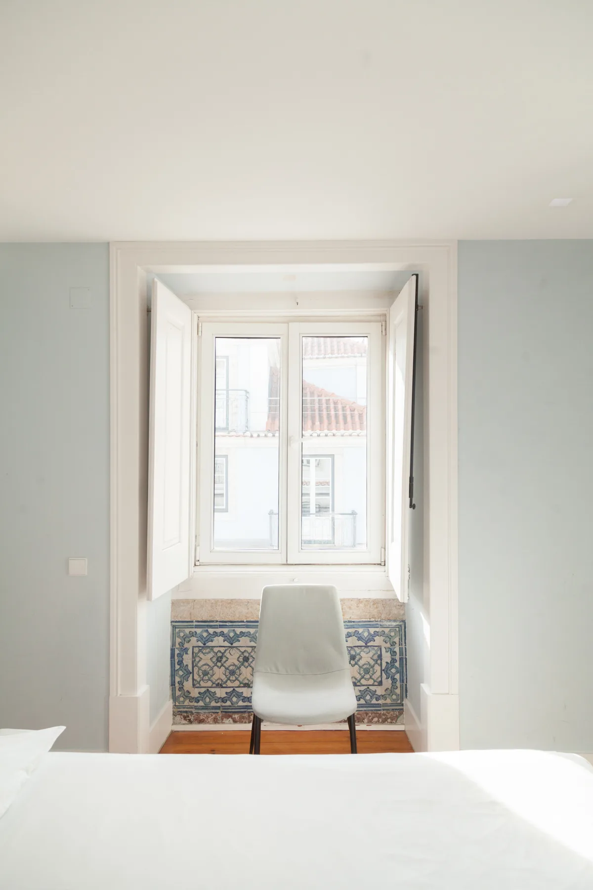 A bright bedroom with a chair positioned in front of a large window.