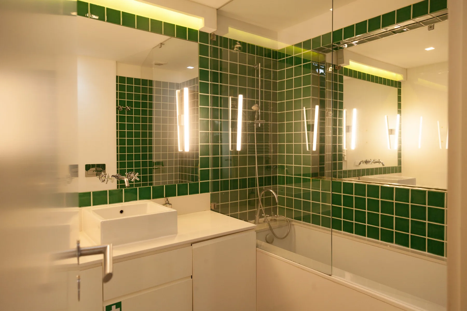 A bathroom vanity and sink sit beside a glass-enclosed shower.