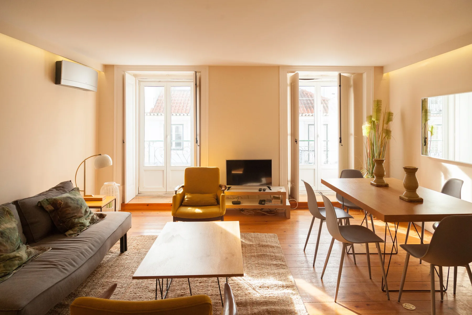 A bright living and dining area with seating, a coffee table, and a television.