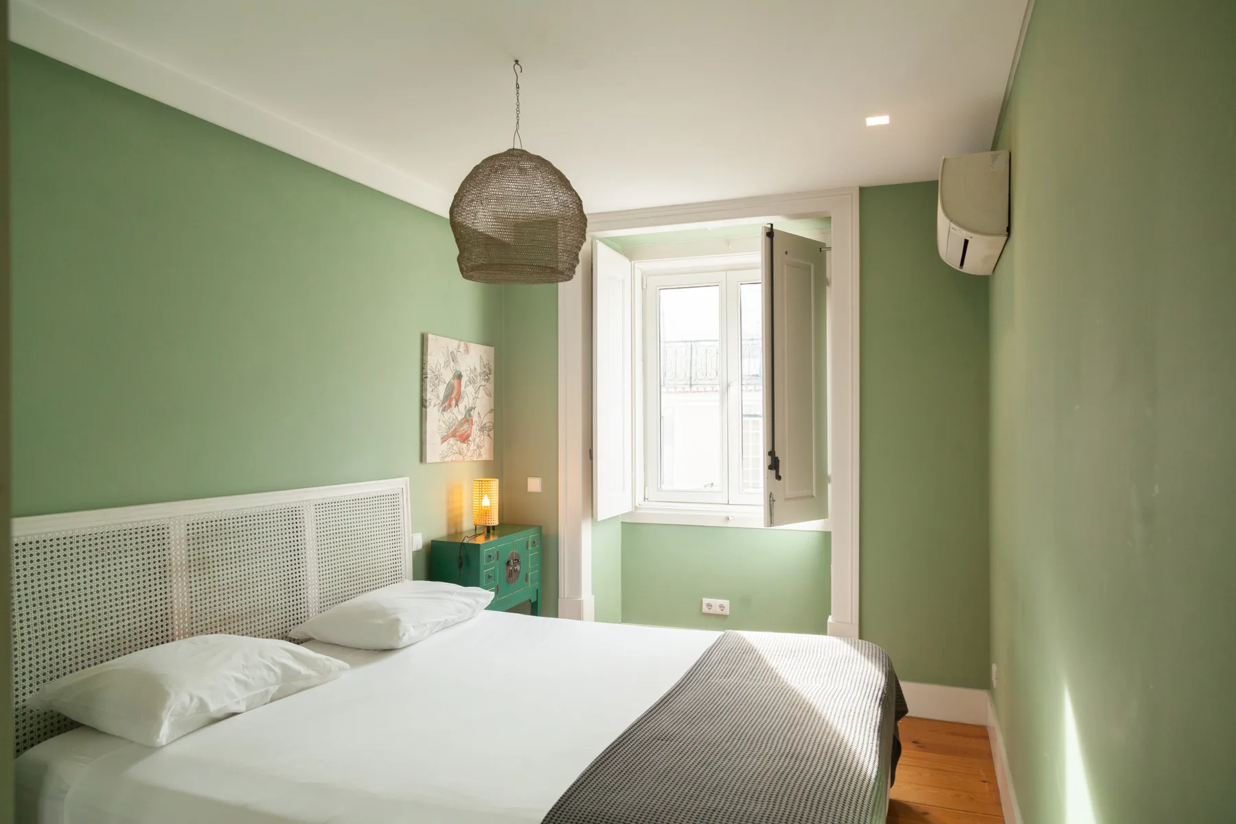 A bedroom with a bed, green walls, and a window.