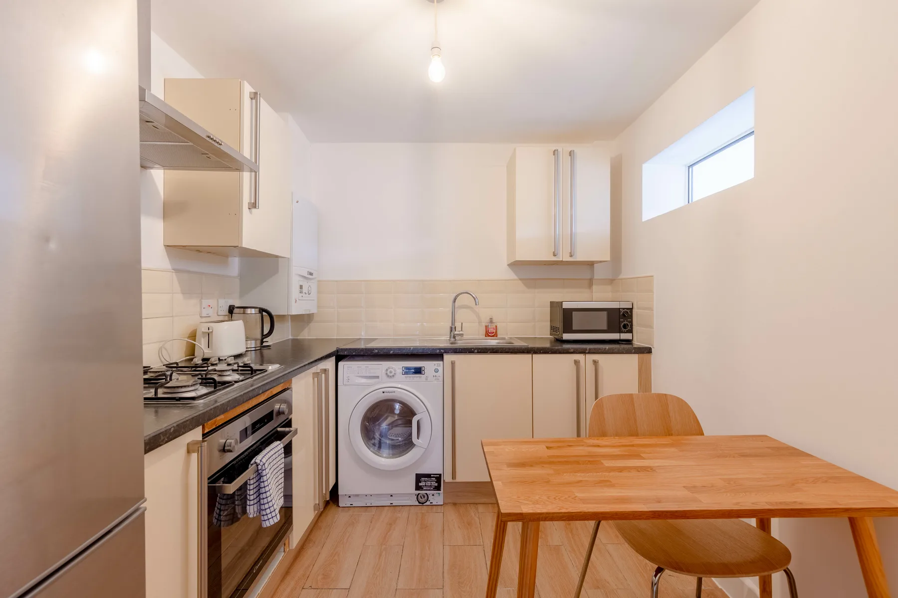 Una cocina compacta con mesa de comedor y lavadora.