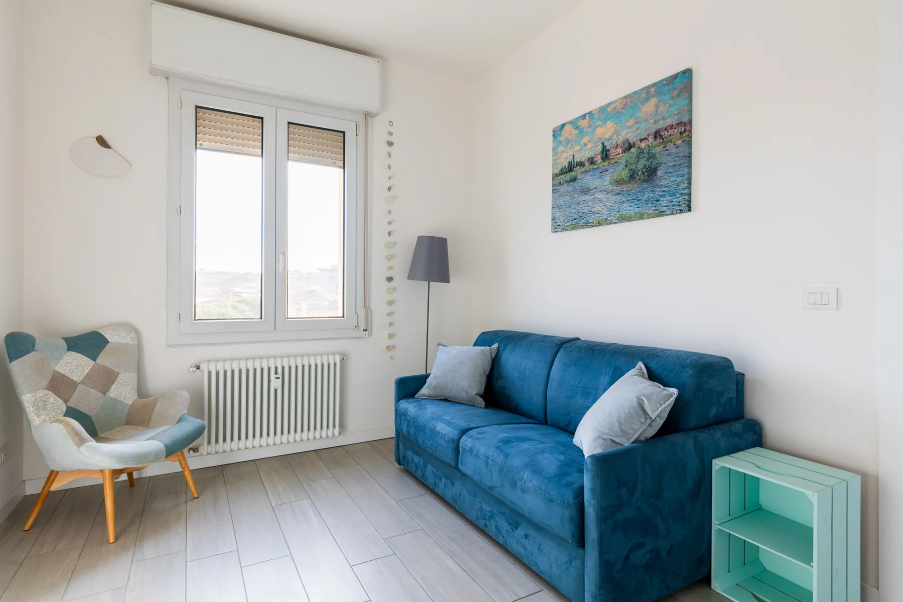 Una sala luminosa con asientos azules y una pintura de paisaje colorida.