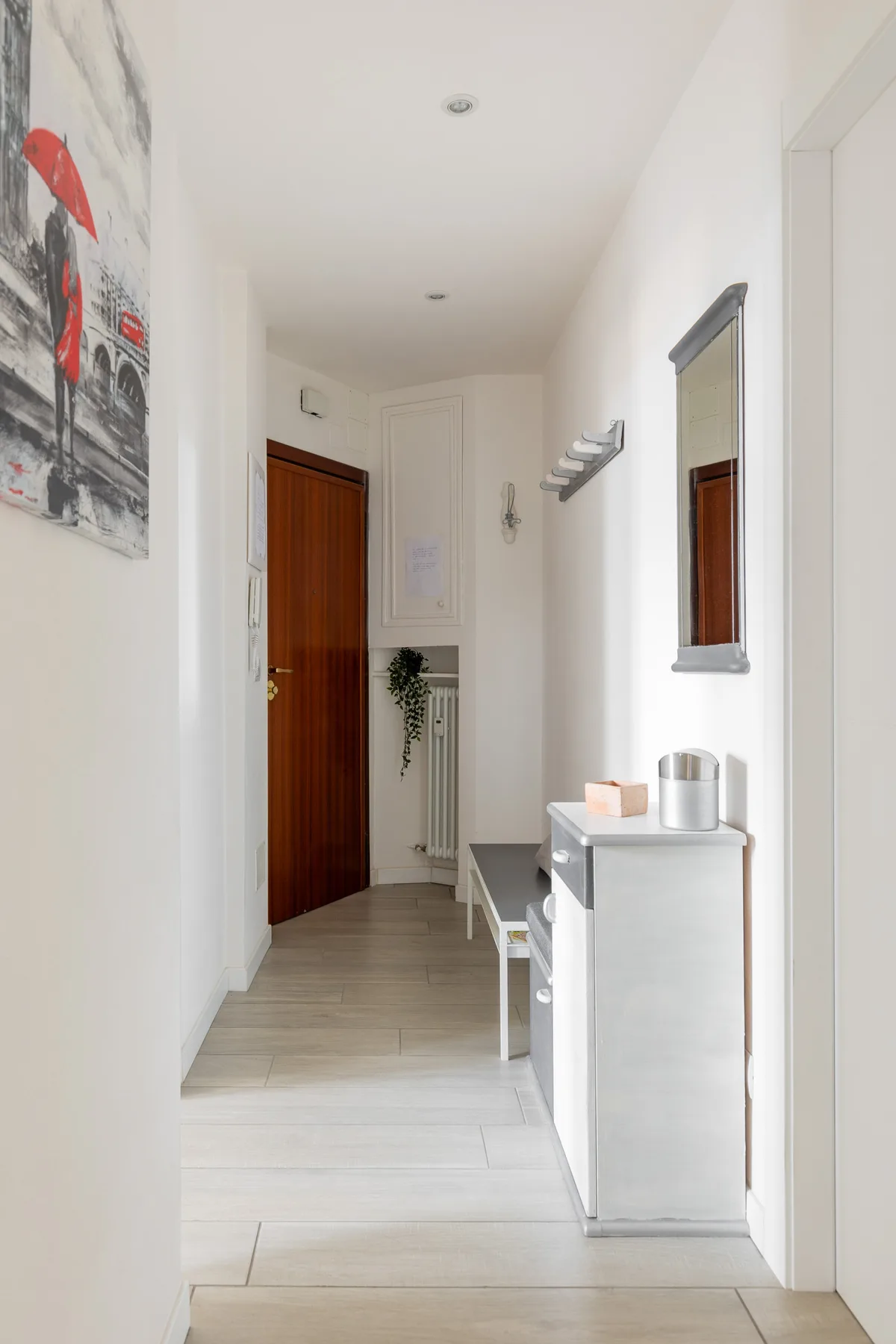 Un pasillo luminoso con una puerta de madera y una consola estrecha.
