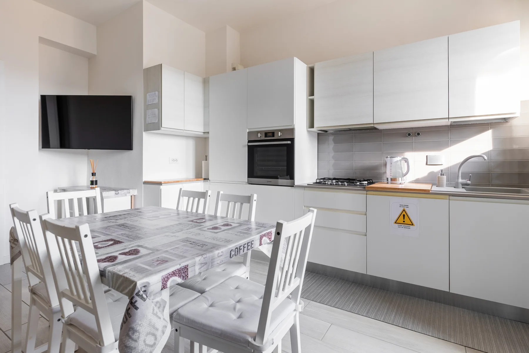 Una cocina y comedor luminosos con gabinetes blancos y una mesa.