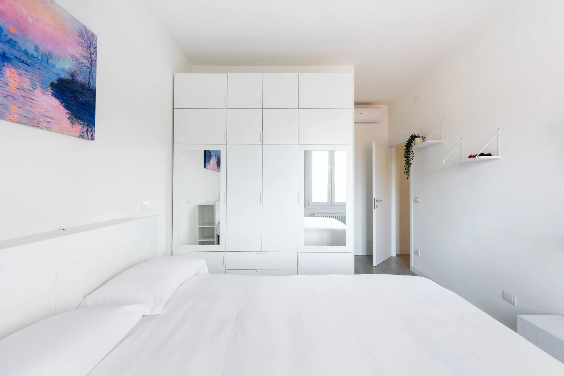 Un dormitorio luminoso con una cama grande y armarios blancos empotrados.