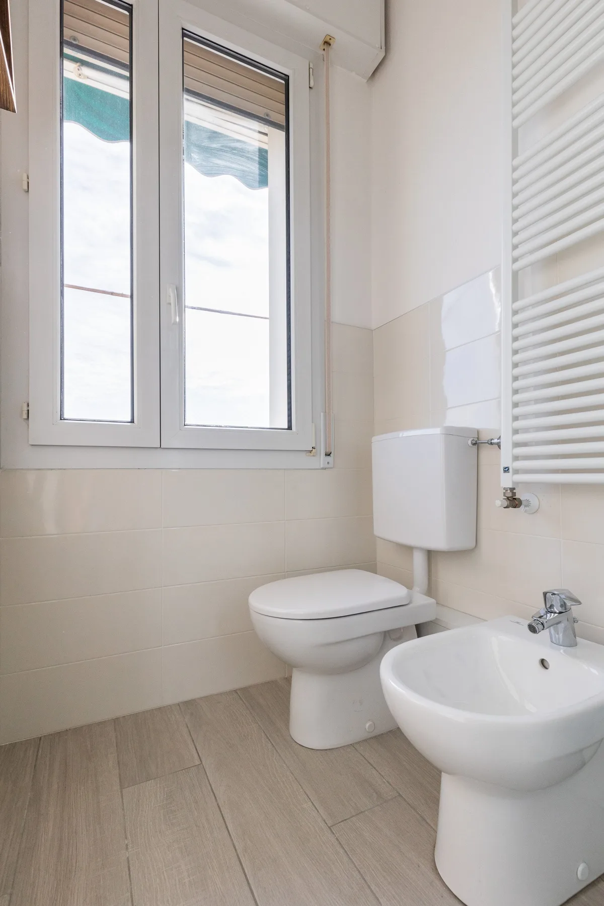 Un baño luminoso con inodoro, lavabo y ventanas altas.
