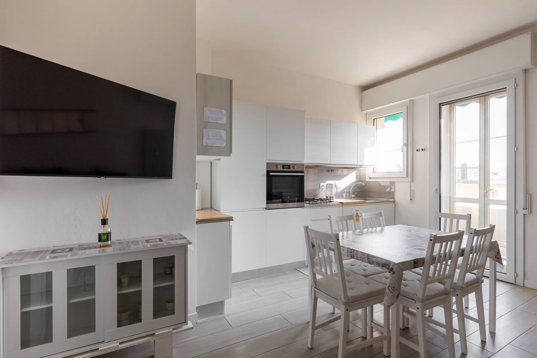 Una cocina y comedor luminosos con gabinetes blancos y una mesa de comedor.