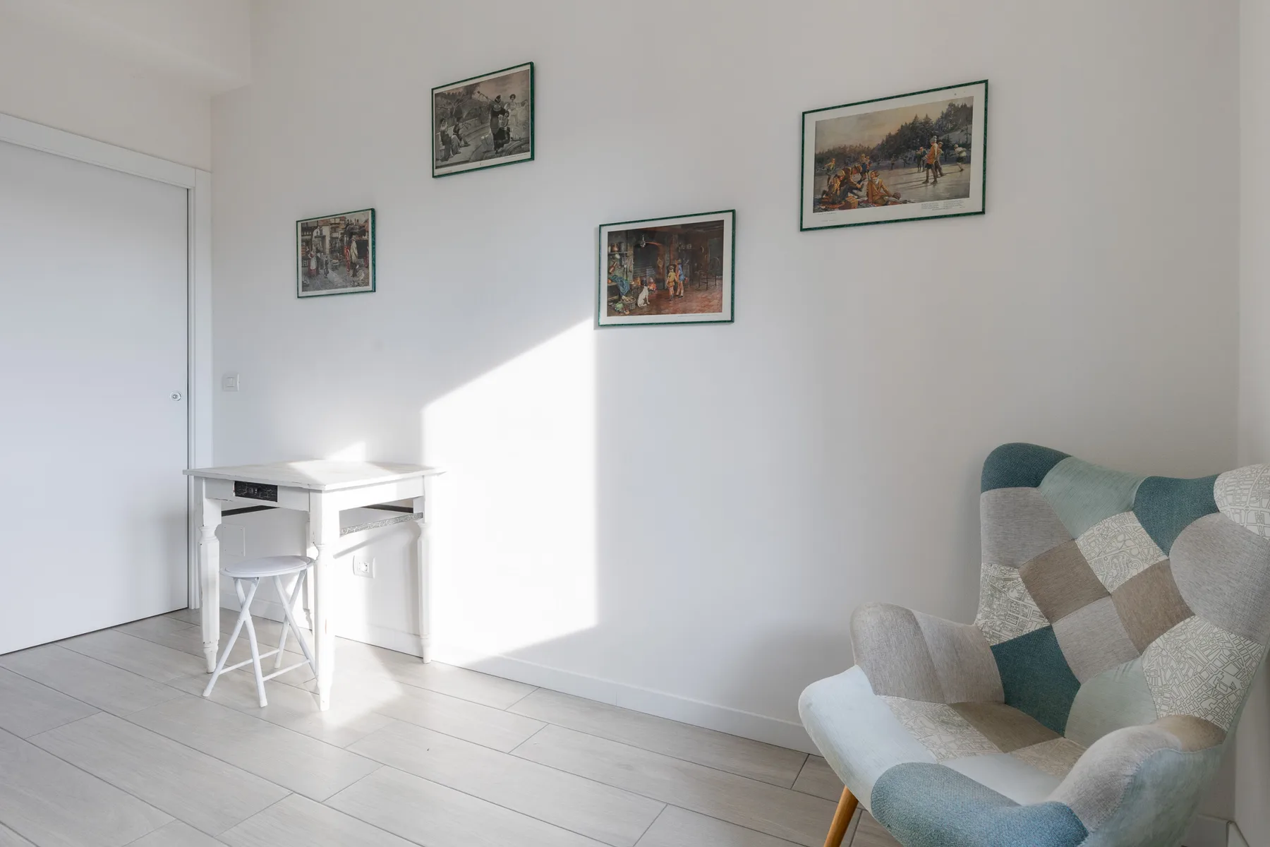 A bright sitting area with a patterned armchair beside a small white table.