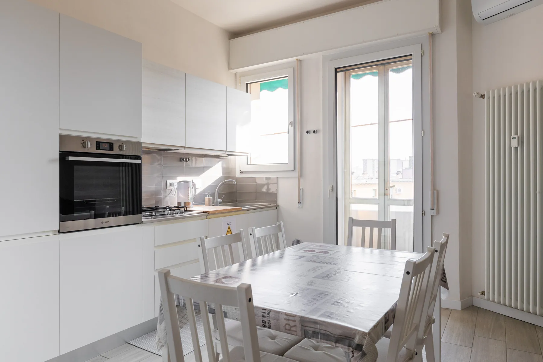 Una luminosa cocina y comedor con una mesa junto a grandes ventanas.