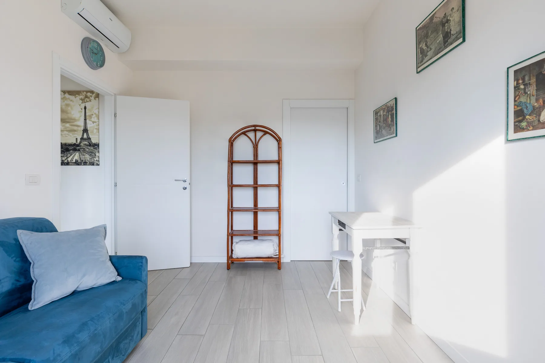 Una habitación luminosa con asientos azules, un estante de madera y un escritorio blanco.