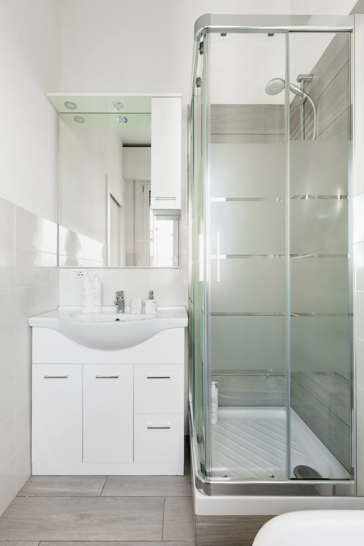 Un baño luminoso con un lavabo junto a una ducha de vidrio.