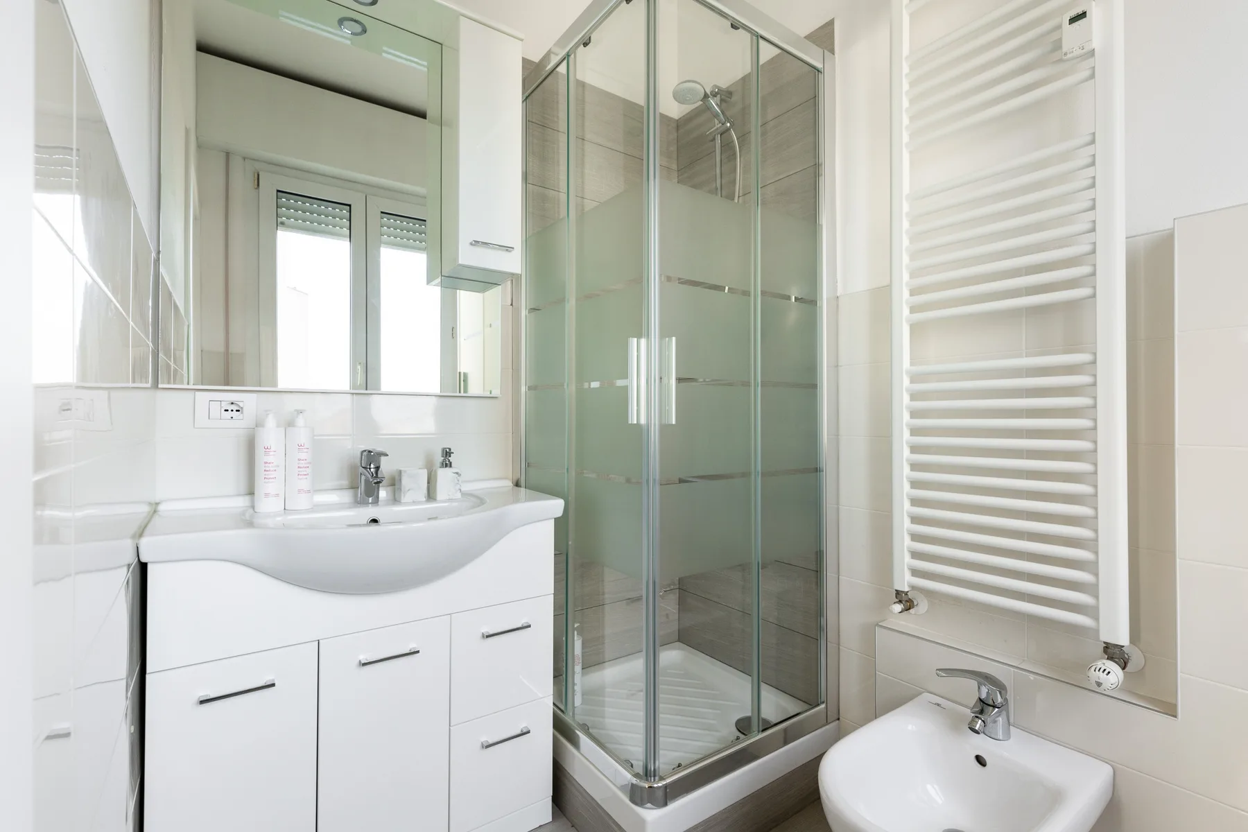 Un baño luminoso con ducha de vidrio, mueble de lavabo y bidé.