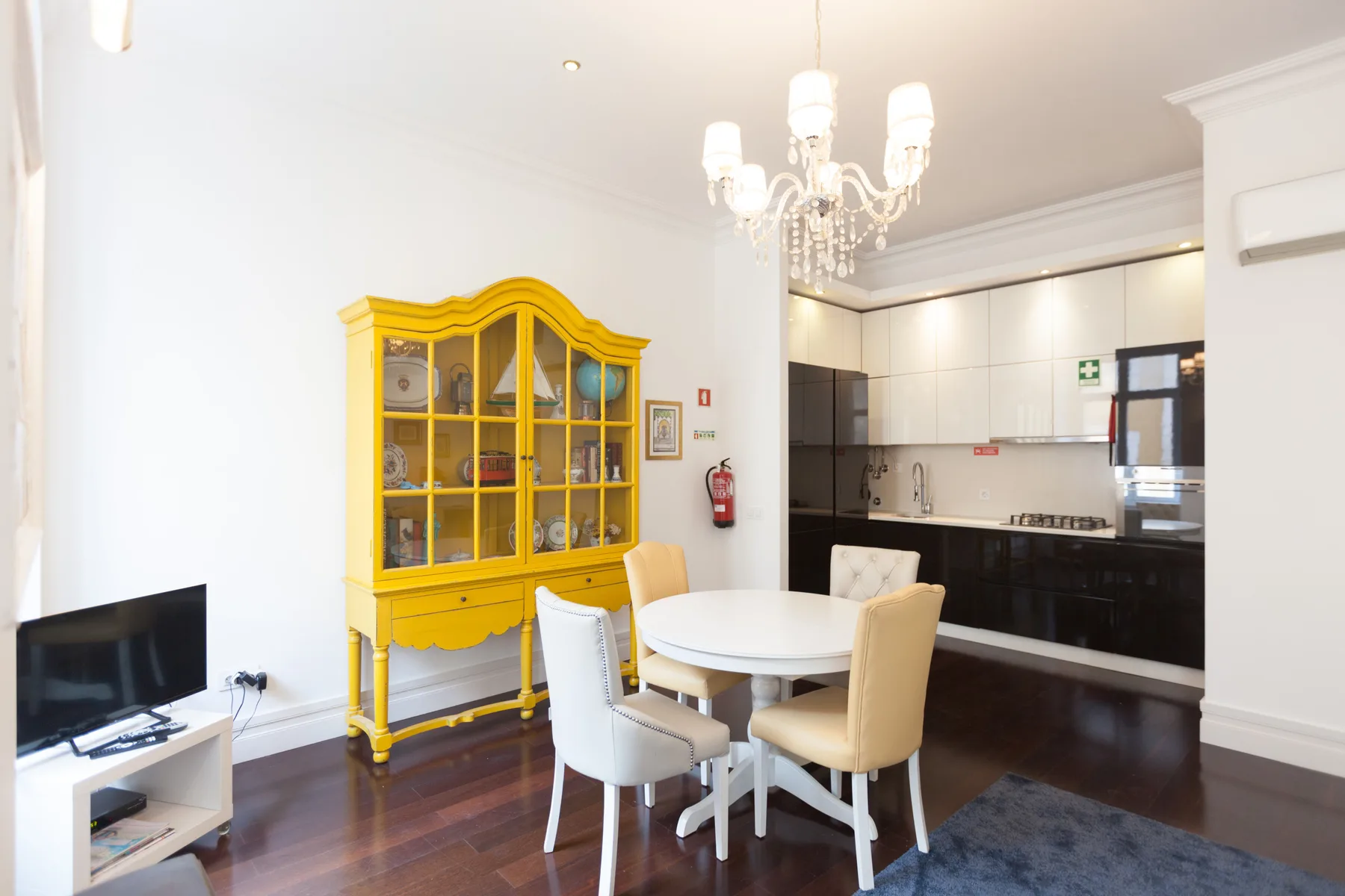 Comedor con una mesa redonda y un armario expositor amarillo junto a la cocina.