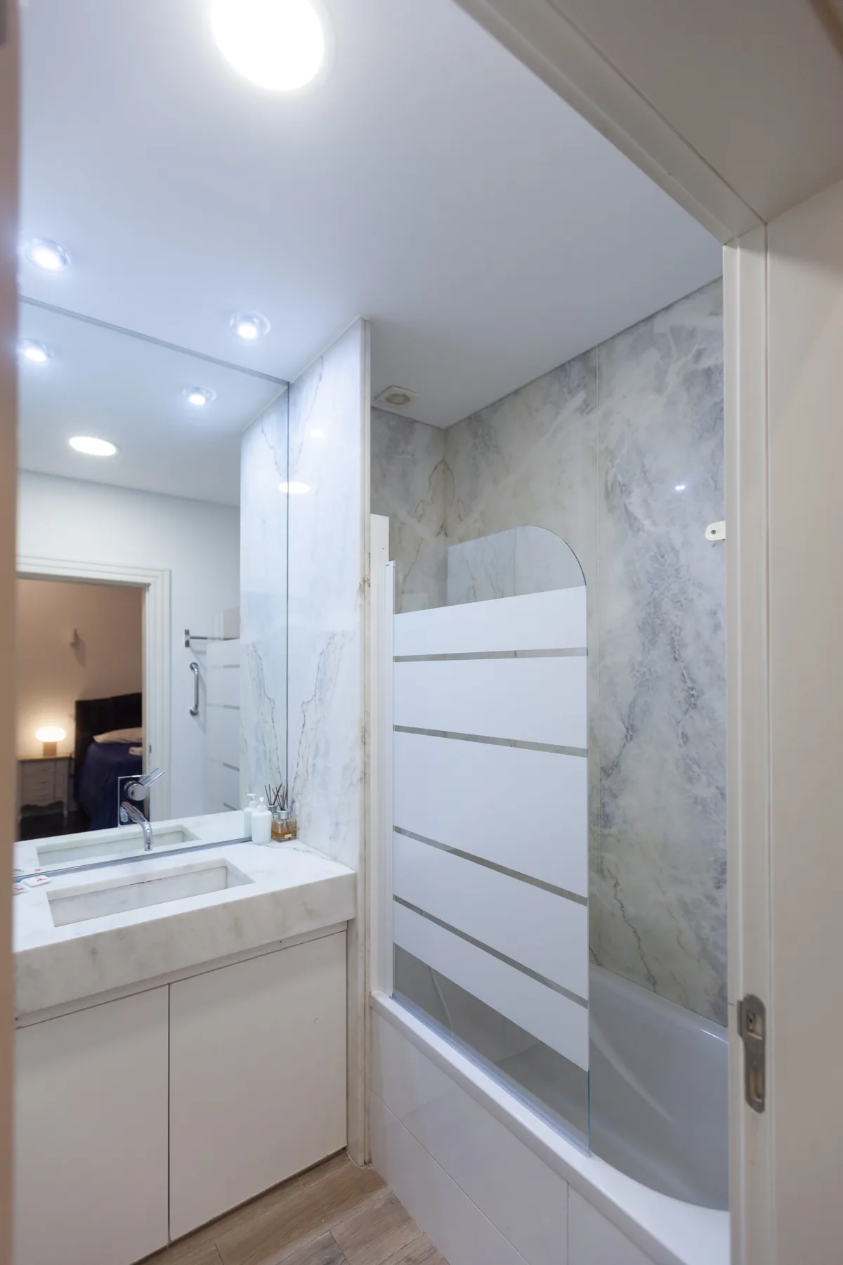 Un baño luminoso con un lavabo de diseño marmolado y ducha.