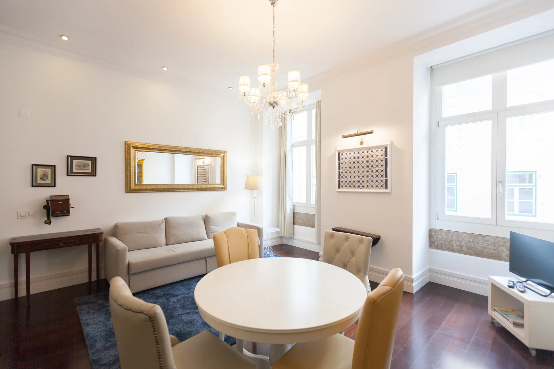 Una luminosa sala de estar y comedor con asientos alrededor de una mesa y grandes ventanas.