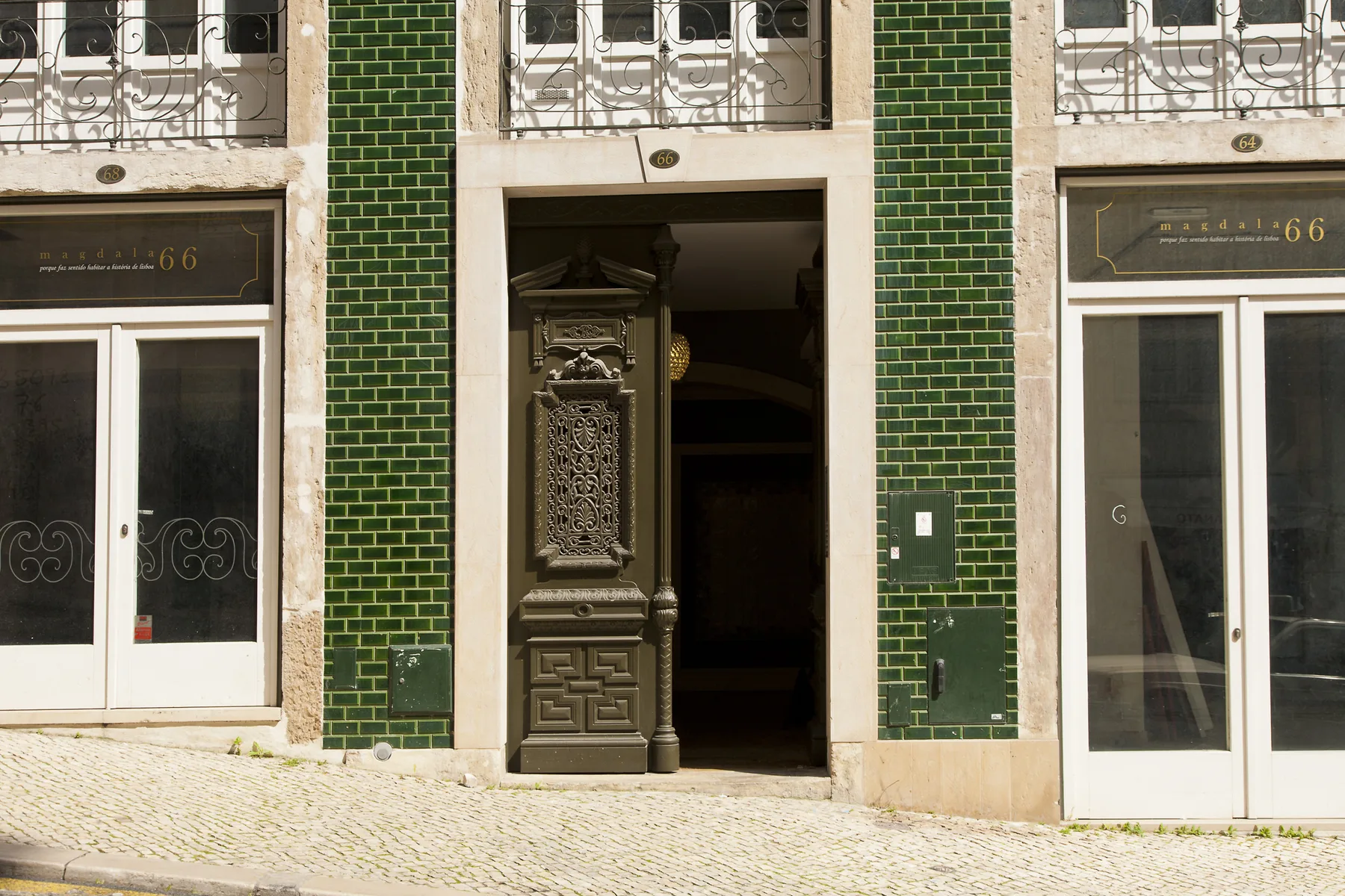 Entrada de un edificio con azulejos verdes y detalles de metal ornamentados.