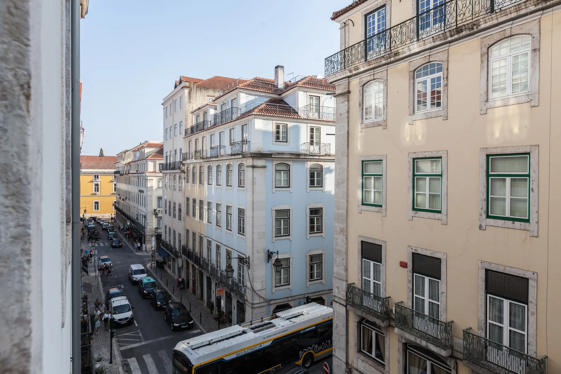 Una calle urbana flanqueada por edificios de varias plantas, con coches y un autobús abajo.