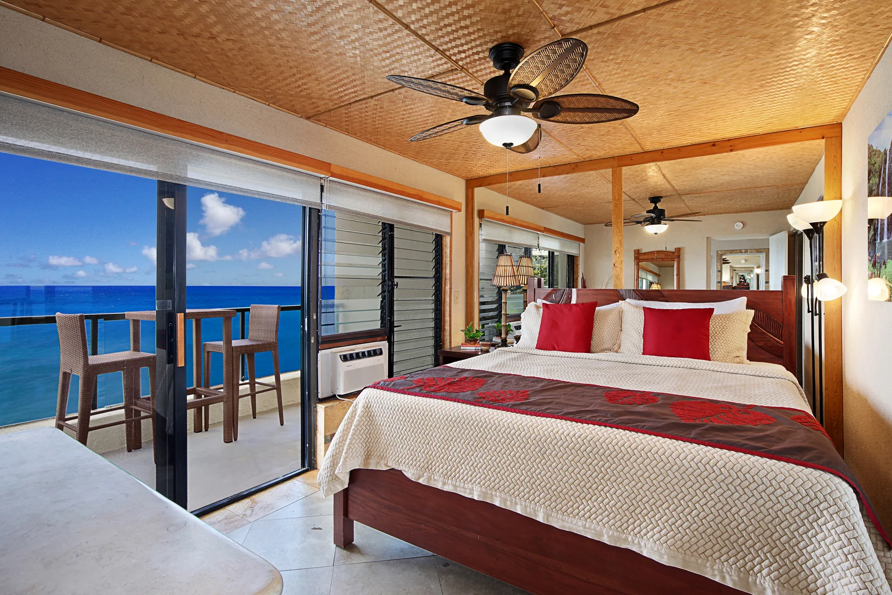Un dormitorio con una cama grande frente a puertas corredizas de vidrio con vista al mar.