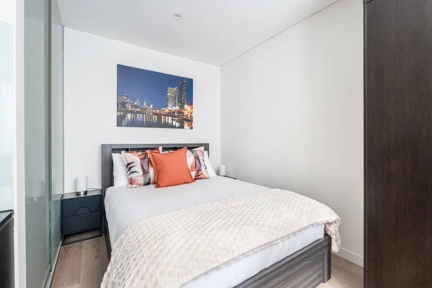 A bedroom with a bed dressed in white bedding and colorful pillows.