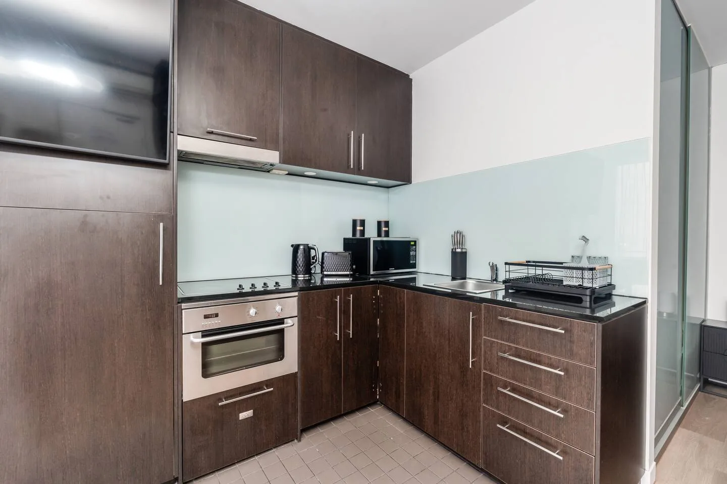A compact kitchen with dark cabinets, a built-in oven, and a countertop.