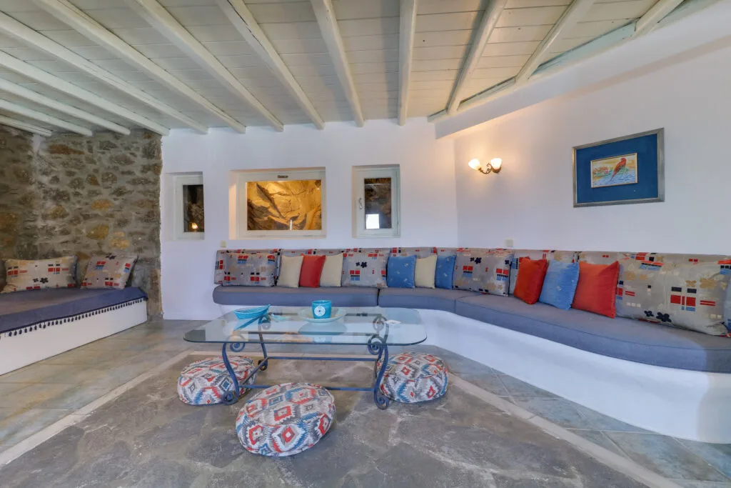 A living room with built-in seating, patterned cushions, and a glass coffee table.