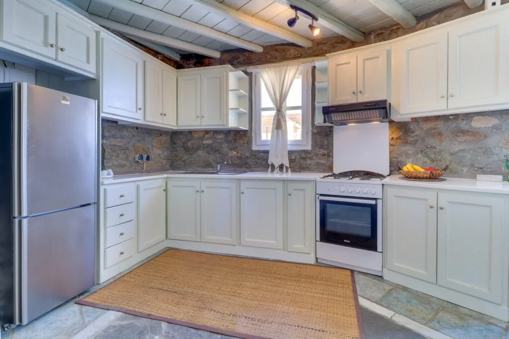 A kitchen with white cabinets, a refrigerator, and an oven.
