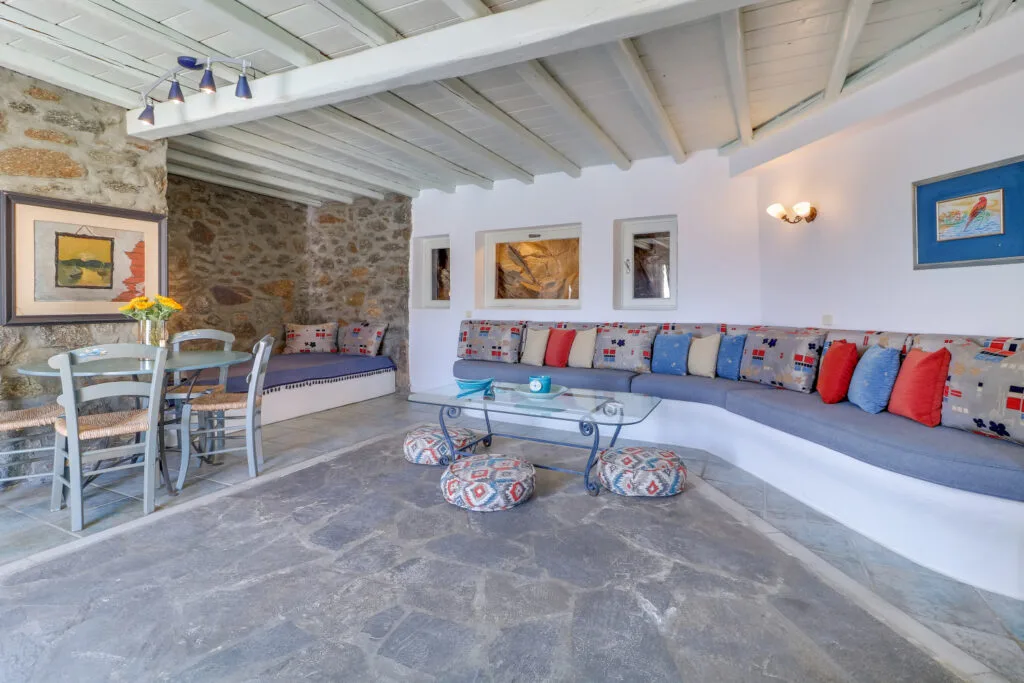 A bright living room with built-in seating, colorful cushions, and a glass coffee table.