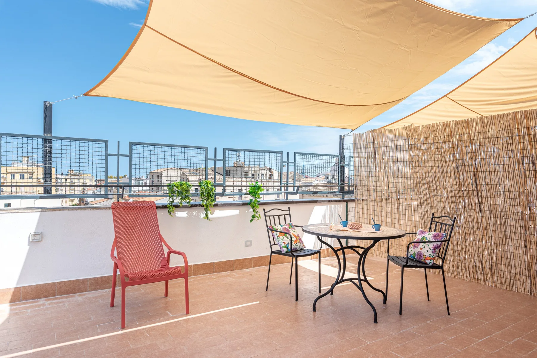 A rooftop terrace with outdoor seating beneath shade sails.