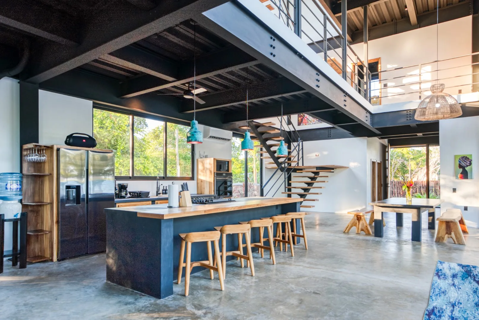 A spacious kitchen and dining area with a counter beneath an open staircase.