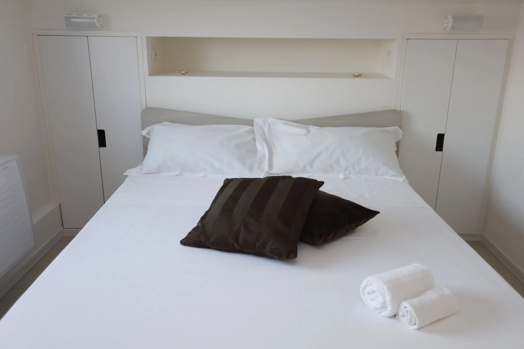 A bedroom with a neatly made bed and folded towels.