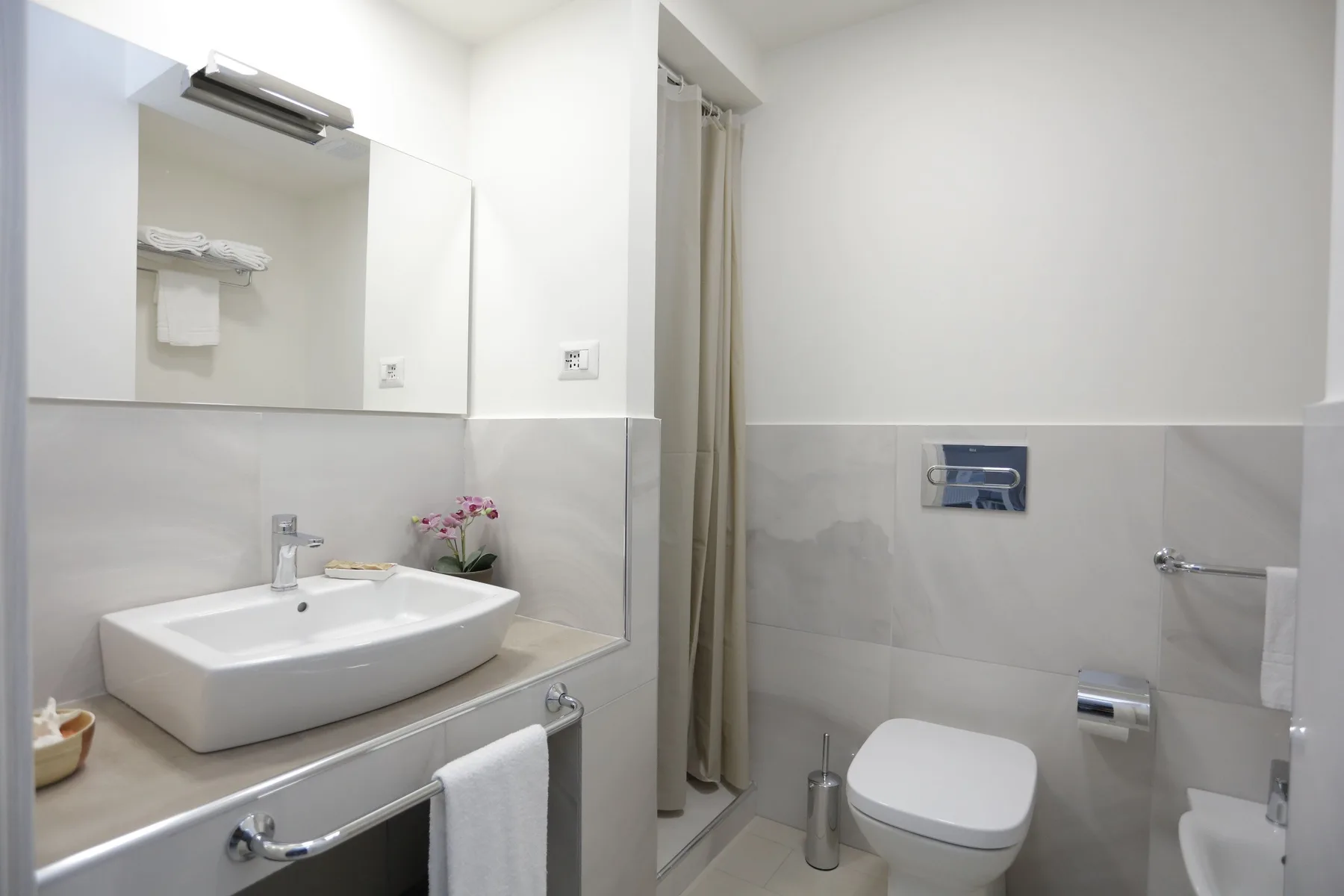 A bathroom with a sink, mirror, shower curtain, and toilet.