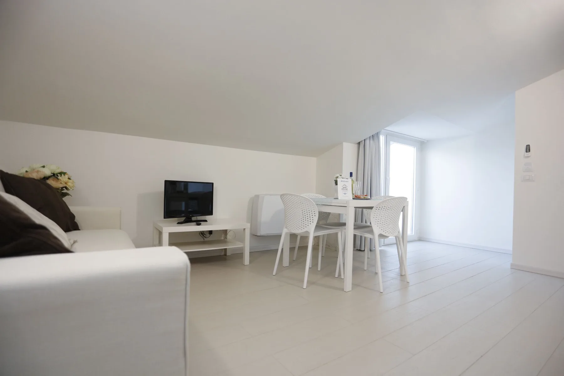 A bright living and dining area with seating, a television, and a dining table.