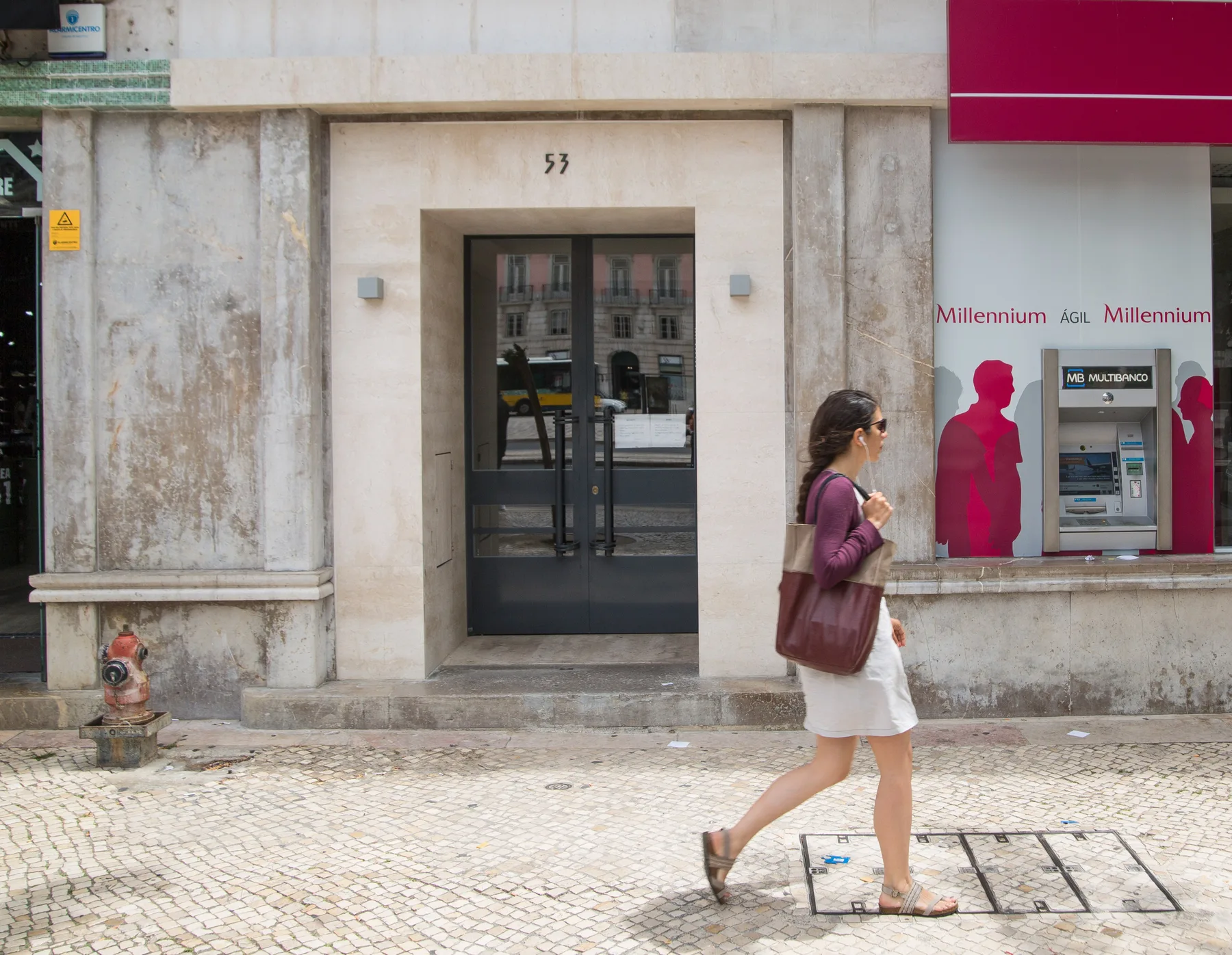 Una calle urbana con la entrada de un edificio de piedra y un cajero automático.