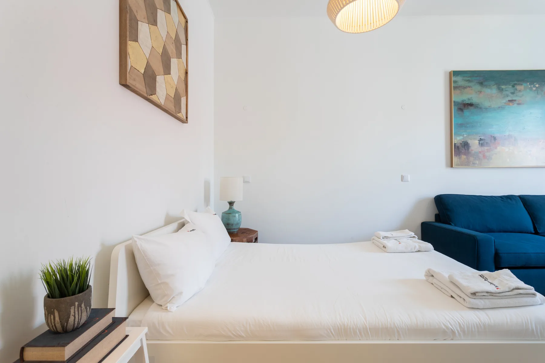 Un dormitorio luminoso con una cama blanca y asientos azules.