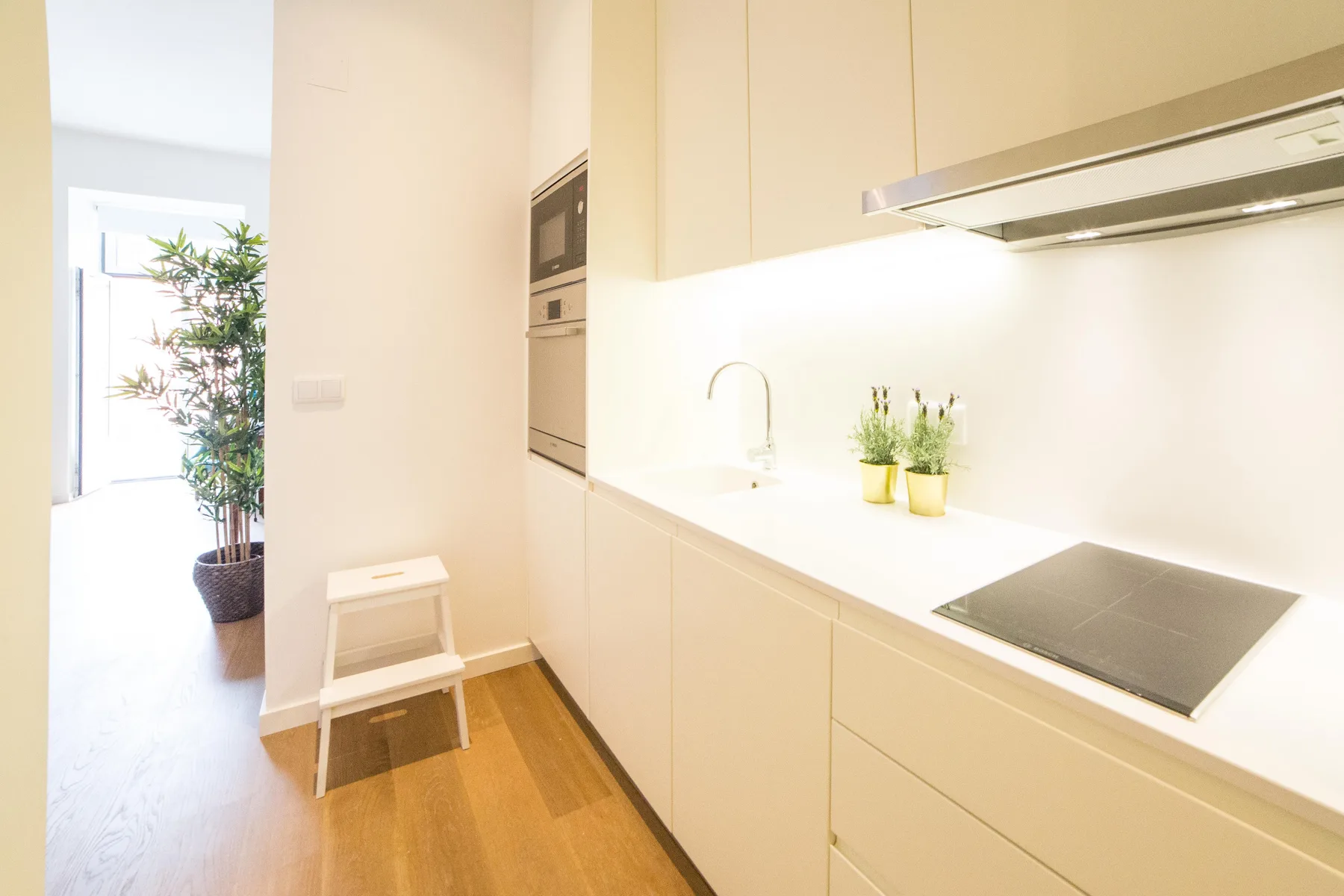 Una cocina compacta con placa de cocción, encimera y un taburete pequeño.