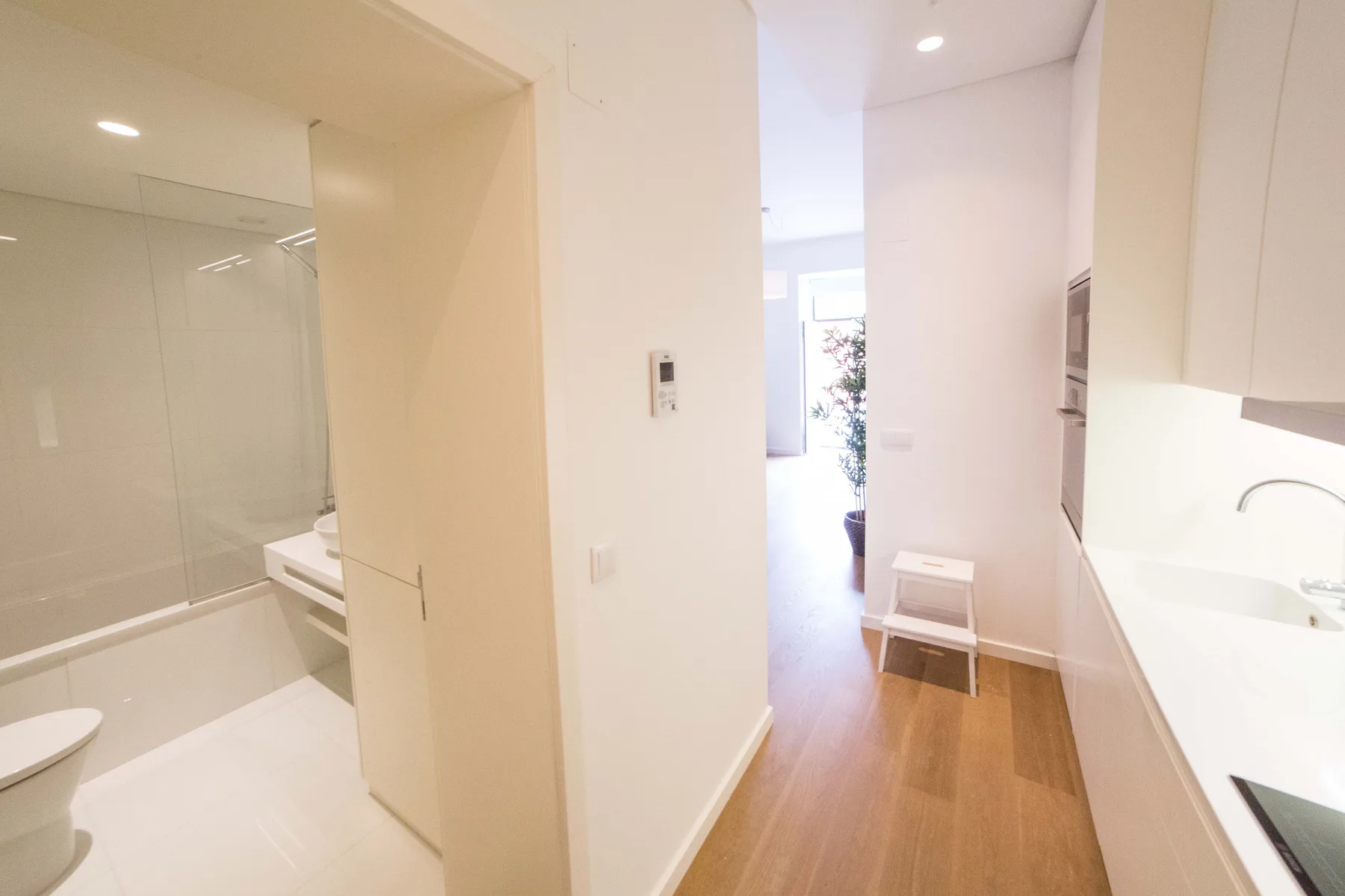 Un pasillo luminoso del apartamento da a un baño y una pequeña zona de cocina.
