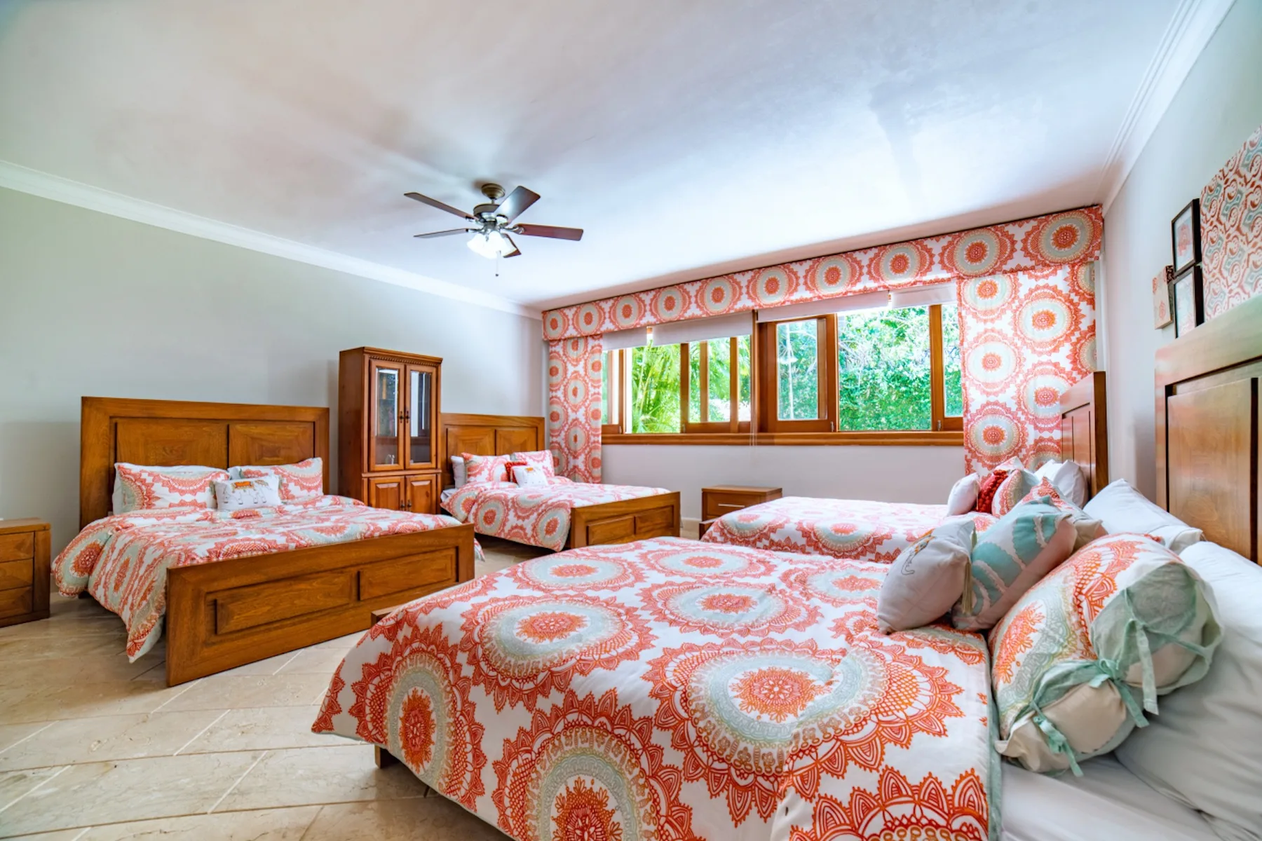 Un dormitorio con ropa de cama estampada y una ventana amplia con vistas a la vegetación.
