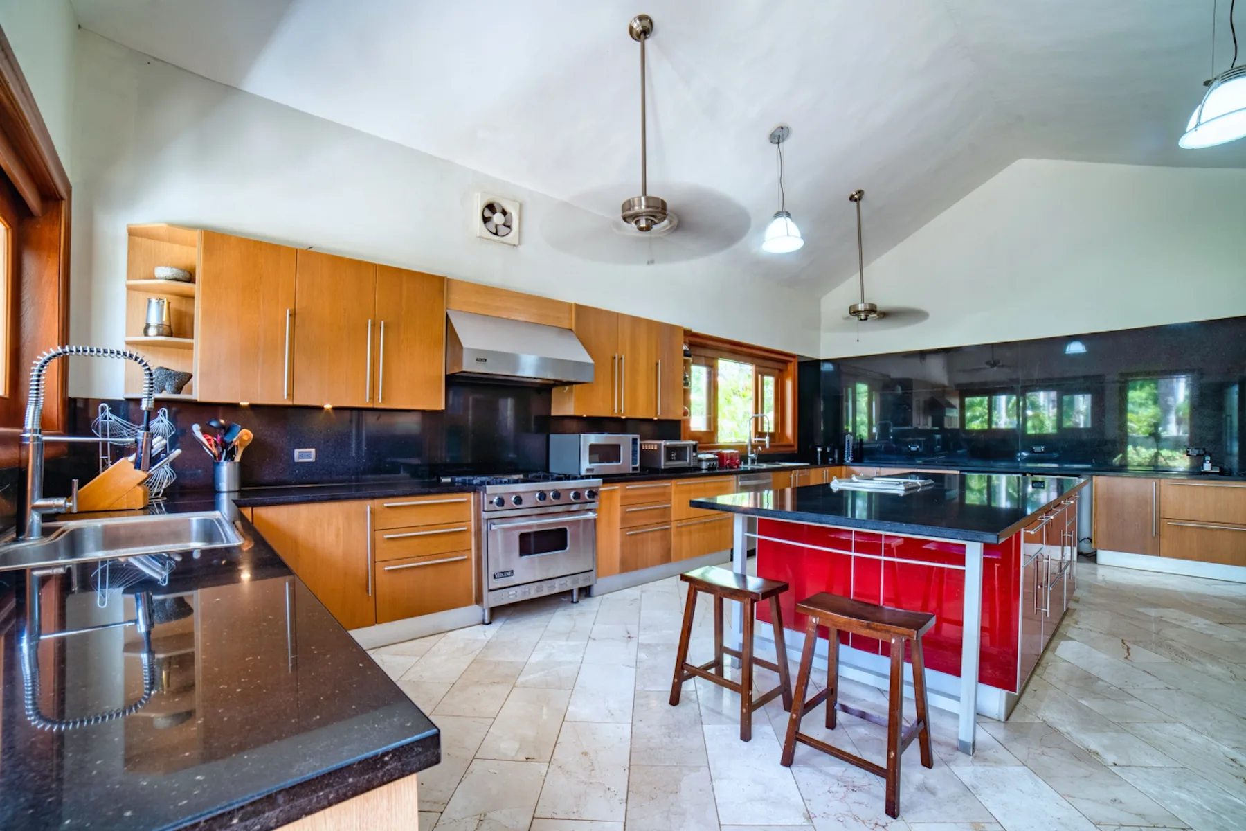 Una cocina amplia con gabinetes de madera, encimeras oscuras y una isla roja.